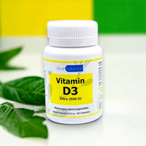 Vitamin D3-Tablettendose von Blue Balance ETH Meditec arrangiert in einem minimalistischen weißen Raum, akzentuiert durch frische grüne Blätter neben der Dose, was Natürlichkeit und Gesundheit symbolisiert.